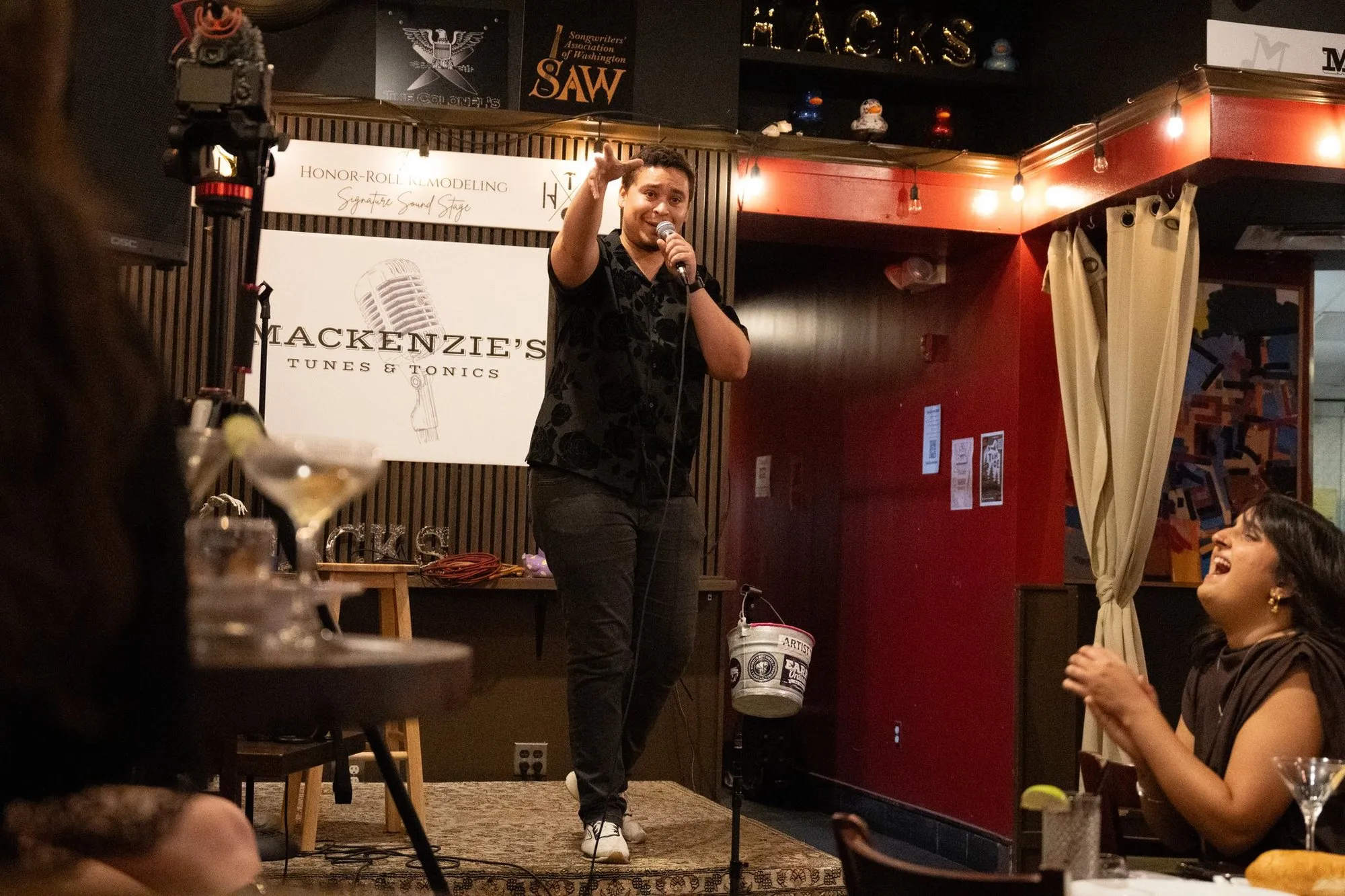 A comedian pointing into the crowd as a guest doubles over laughing